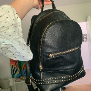 Ryggsäck i skinnimitation! - Liten/medel-stor ryggsäck i skinnimetation med gulddetaljer! Väskan är ifrån Faith och köptes ifrån Zalando. Saknas en detalj på dragkedjan till det lilla facken (fråga om bild i chatten), men annars i riktigt bra skick! 
