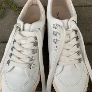 Vita sneakers - Vita sneakers från Zara med stjärnor vid snörningen. Nästintill oanvända, har använts två gånger max. Därför bra skick! Passar mig som har 38 i andra skor så de är större i storleken. Köparen står för frakten (: