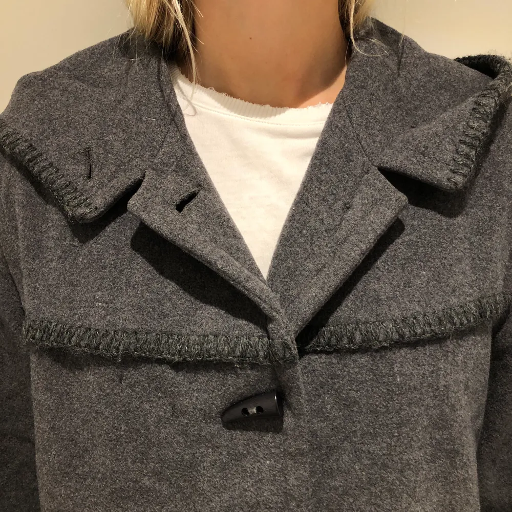 Grå kappa med huva i tjockt material och superfin kvalité. Den har svarta spännen framtill och är från märket PTA. Nyskick! Skriv gärna för fler bilder! Kan mötas upp eller skickas men köparen står då för frakten <3 (Säljer just nu massa fler kappor och jackor så kolla gärna in min profil!). Takit.