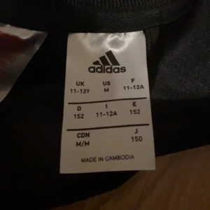 Adidas - Detta är en Adidas tröja / kofta. Den fungerar fint och har inga problem. Dragkedjan fungerar perfekt och det behövs ingen hjälp för att knäppa den av föräldrar. Tröjan säljs för mindre än vad den kostar även om den ej är använd pga inget kvitto kvar.