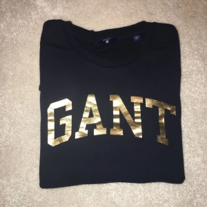  - Säljer en populär GANT collage tröja i storlek small. Färgen är marinblå med guldigt tryck. 