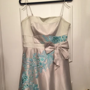  - Använd 2 gånger på bröllop, axelbanden är avtagbara. Det finns en liten fläck vid blommorna men som går att tvätta bort.  Köpt i USA direkt från Karen Miller butiken. Ny pris; ca 3000