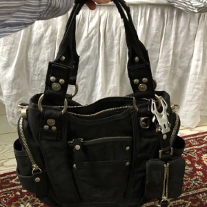  - Väska från George Gina & Lucy, en svart medelstor och rymlig handväska med silvriga detaljer. Finns korta ”handtag” och ett justerbart axelband som även går att ta bort. Ingår även den lilla ”väskan” på bild 3.   Nypris ca 1100:-  