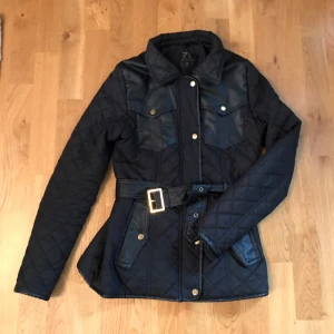  - Svart quiltad jacka med skinnimitations detaljer. 