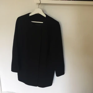  - Svart kappa köpt på humana Stockholm. Jackan har ingen lapp med märke, men är bra kvalite och knappar som inte syns när jackan är stängd. Strävt material, ingen krage.