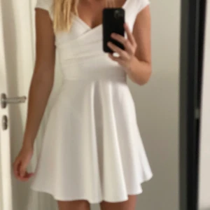 Vit klänning  - Vit omlott klänning från Bubbleroom. Funkar till alla typer av tillställningar skolavslutning konfritmation student. Fin urringning & går att ha både off shoulder & vanligt. Tajt upp till & släpper efter midjan.