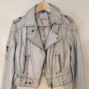  - Silvrig skinnjacka (äkta skinn). Sparsamt använd i bra skick. Strl 38 från märket Rock and Blue.