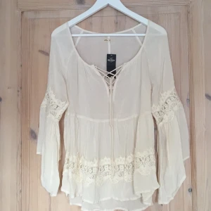  - Söt boho inspirerad blus från Hollister i storlek XS (passar även S). Knyt fram, vida ärmar samt spetsdetaljer. Aldrig använd, prislapp kvar. Nypris 480kr