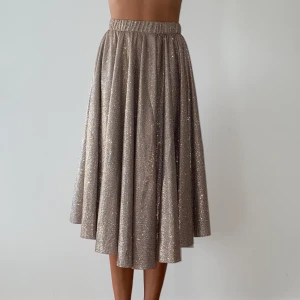 Lena Midi Skirt Dusty Camel - Supersnygg kjol i glitter från VILA. Kjolen har ett fint fall och passar lika bra till vardags som till fest. Nypris 500kr. Använts ca 3 gånger. - Stum, kvalitet - Resår i midjan - Fodrad