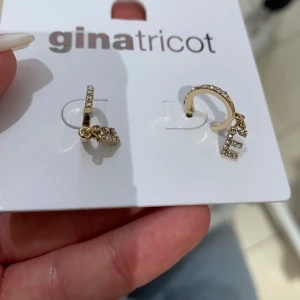 Örhängen bokstav E - Ett par guld imiterade örhängen från Gina. Oanvända med lapp kvar