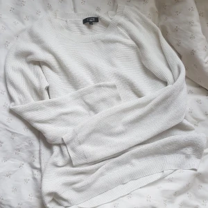 Vit långärmad stickad tröja från BikBok - Säljer denna tröja från BikBok. Passar bra året om! Halsen är rundad och tröjan är enkel och stilren i sin design. Inte använd på ett par år och därför passar den bättre hos någon annan som ger den mer kärlek!