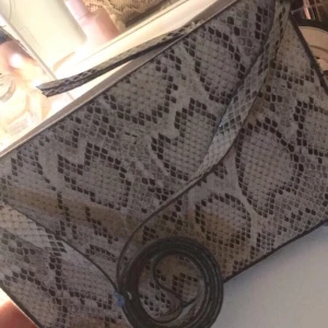 Ormskinnsmönstrad väska - Säljer min jätte fina ormskinnsmönstrad väska. Jag köpte den för 150kr från H&M. Den har jag aldrig använt eftersom jag tycker att den inte passar min stil riktigt. Mer bilder eller frågor kom priv❤️🌸 Pris kan diskuteras. Frakten står köparen för❤️ 