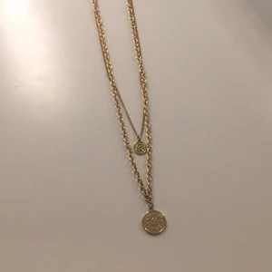 Guldigt dubbel halsband - Ett guldigt dubbel halsband med 2 guldiga berlocker