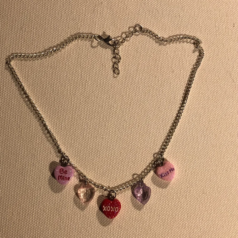 Ett halsband med silverfärgad kedja och fem små hjärtan som berlocker . Asusteet.