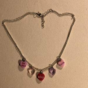 Ett halsband med silverfärgad kedja och fem små hjärtan som berlocker 