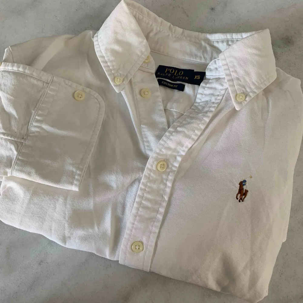 Vit Ralph Lauren skjorta i storlek XS. Modell custom fit så den är figursydd. Fint nyskick!  Köpare står för frakten (39kr)💝. Skjortor.