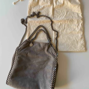  - Säljer nu min Stella mccartney väska i storlek Falabella mini tote. Den är ljusgrå och i ett superbra skick, inga defekter på den! Jag har köpt den på blocket för nypris, inga skambud!!