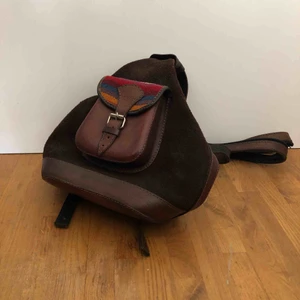  - Väska i fint skick. Kan med blixtlåset både användas som ryggsäck och stängas så det bara blir en rem. Har ett litet innerfack med blixtlås. Osäker på material men tror det är något slags läder.