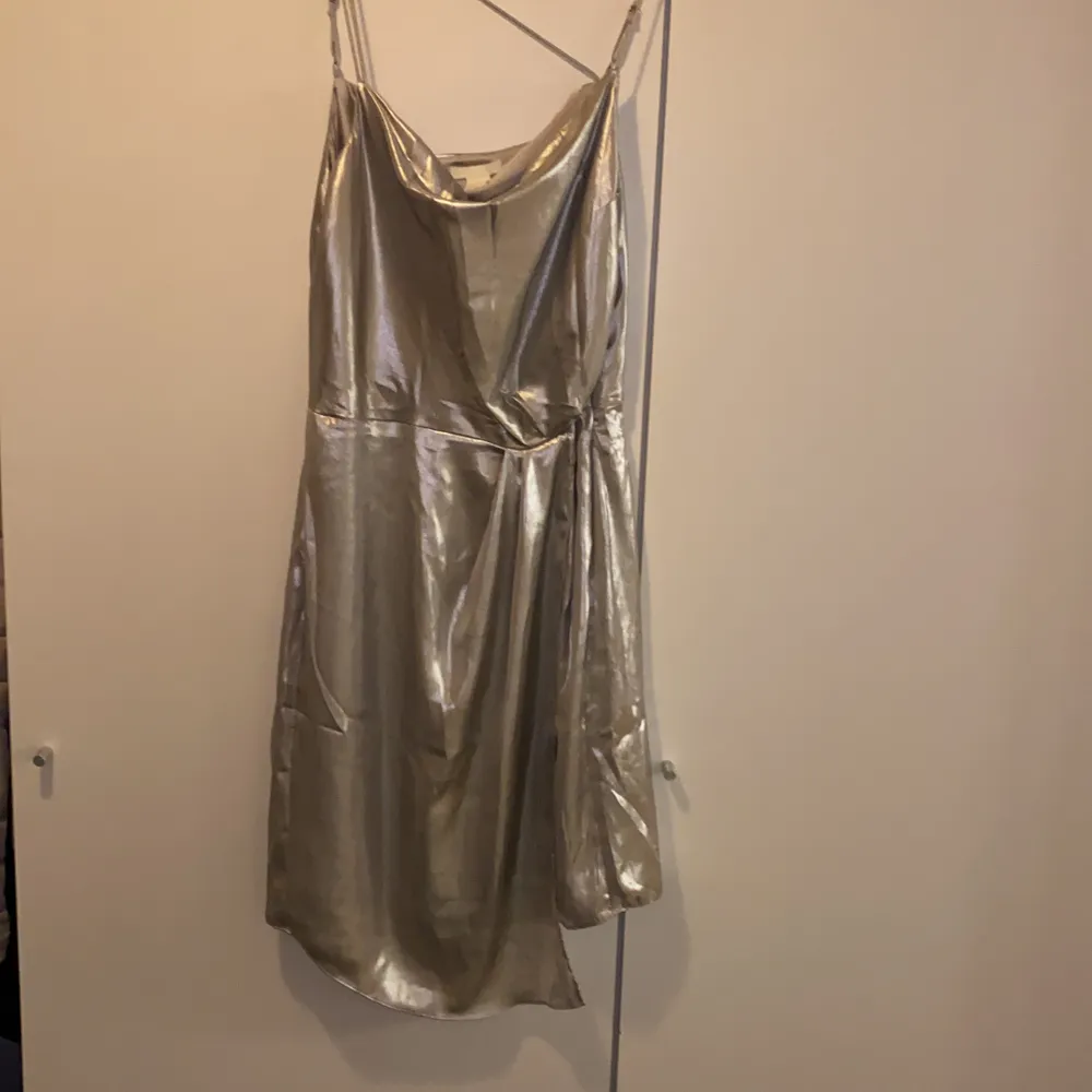 Miniklänning från H&M! Detaljer med metallictråd. Silver färg! Knäppning i sidan med dragkedja. Använda en gång!!!! Det ser ut som nytt! 🙂. Klänningar.