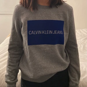 Calvin Klein - sweatshirt, strl M, 150kr - Säljer denna mysiga gråa sweatshirt med ett blått tryck, från Calvin Klein, i strl M, för 150kr. Den är i jättefint skick och bara använd 1 gång. Frakt tillkommer inte💞