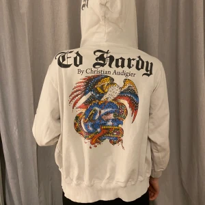 Ed Hardy ziptröja - Fint men använt skick. Några fåtal stenar har lossnat, men är inget som stör. Dragkedjelåset har även gått av (se sista bilden), går dock att använda dragkedjan ändå. Fraktar! BUDA I KOMMENTARERNA!! Avslutas 2:a februari 21.00 