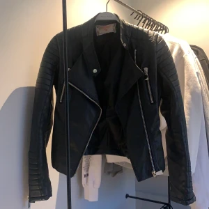  Fejk skinnjacka. -  Fin skinnjacka inte äkta skinn storlek 38 passar alla från XS-S till M beroende på hur man vill att den ska sitta. Ett hål i innerryggen ingenting som man tängker på.