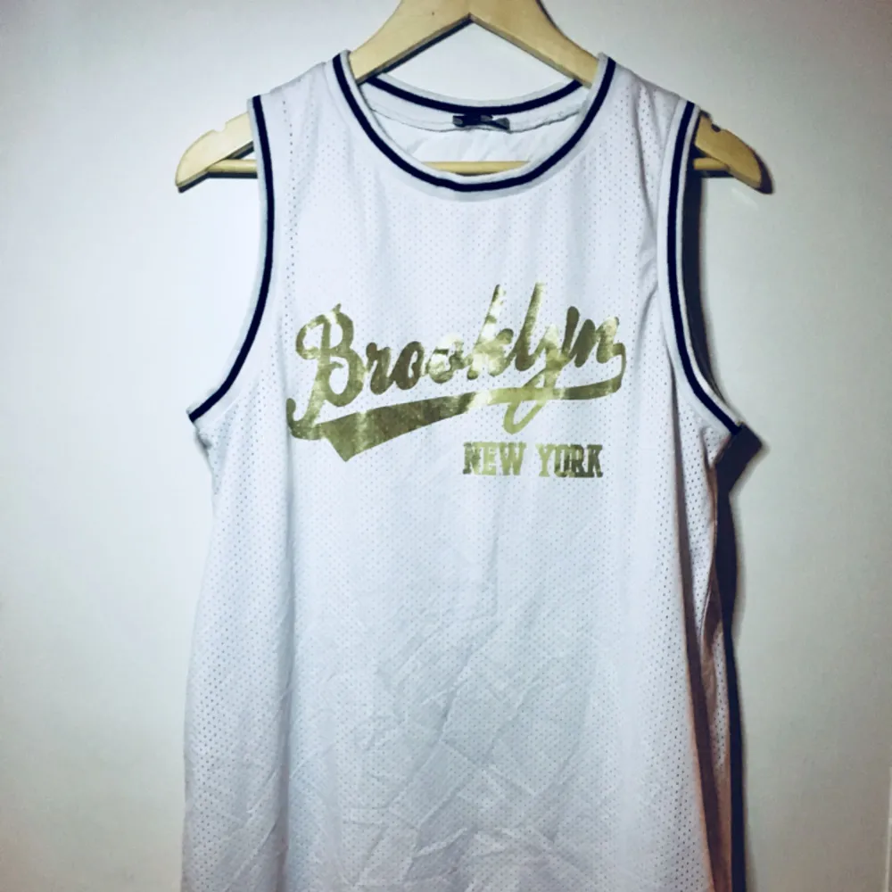 Kort klänning /långt basket linne modell med texten Brooklyn new york i guld. Köpt på Asos och använd fåtal ggr. (Frakt tillkommer om du ej kan hämta på plats). Klänningar.