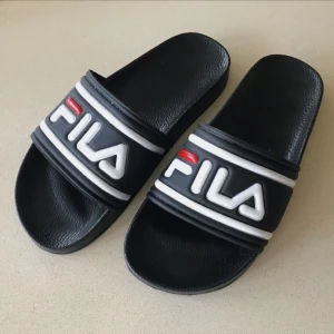  - Fila-tofflor i plast/gummi. Använda endast 1-2 gånger p.g.a att dom är för stora för mig. Som nya! Står storlek 40 i dom, men jag skulle säga att dom passar storlek 39. Köparen står för eventuell fraktkostnad.