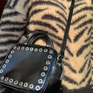 Axelremsväska  - Svart axelremsväska väska från Zara med silvriga detaljer och ett litet handtag, använd fåtal gånger och är därför i bra skick! Väldigt rymlig då formen på väskan är som en fyrkantig box, perfekt för telefon, powerbank, nycklar och mm. Frakt 50kr⚡️⚡️❣️ Men kan även mötas upp