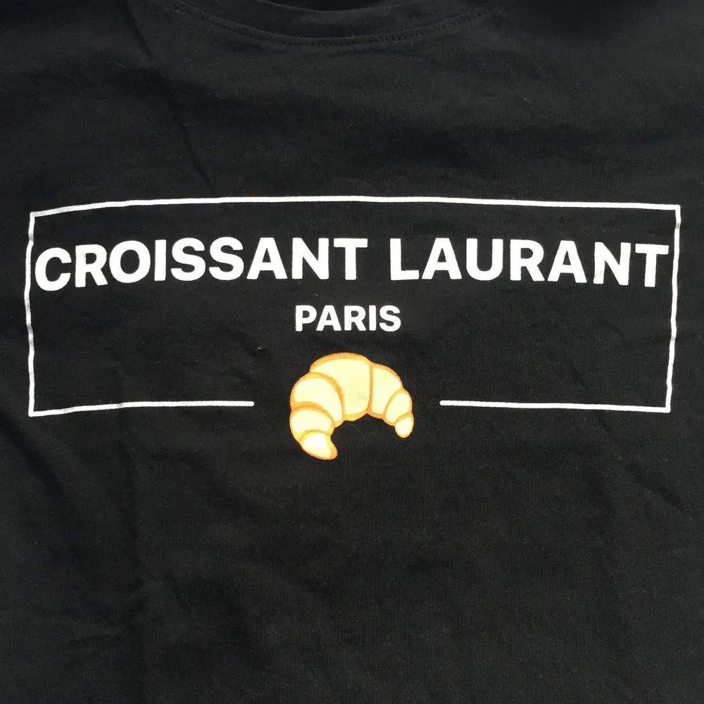 Svart t-shirt med trycket ’croissant laurant 🥐’. Storlek M. Använd ett fårtal gånger(nyskick). Mycket skönt material. Möts upp i Sthlm eller fraktar (köparen står för frakt). Betalas via swish.✨. T-shirts.