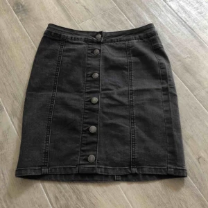 Svart jeanskjol - Snygg jeanskjol i tajt modell med knäppning framtill, köpt på secondhand för länge sen men är knappt använd.  Är i storlek 34 och är inte helt svart utan har lite mörkgrått i sig.😊 50kr + frakt