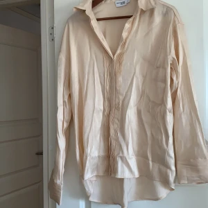 Beiget set - Danny Saucedo x nakd. Skjortan är använd en gång, byxorna är oanvända. Nyskick. Skimmrigt material. Strl 36, men stora i strorleken så passar bättre som 38. Oversized. Nypris 900kr