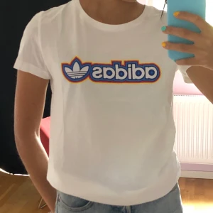 Adidas T-shirt strl S - Fräsch T-shirt med färgglatt tryck. Tunnt tyg vilket passar perfekt till sommaren! Mycket gott skick, säljes då den inte används längre. 