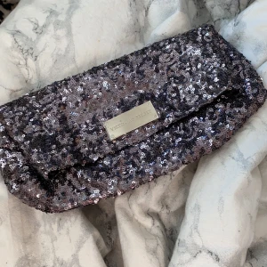 Victorias secret paljettclutch - En clutch från victorias secret, full med paljetter. Kan användas både som clutch men också som neccesär. Kan öppnas 2 på sätt, båda sätten leder till samma fack, dvs det finns bara ett fack. 