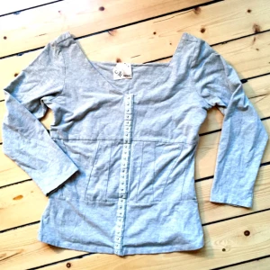  - Grå långärmad tröja från Carin Wester med snygga sömmar i ett mönster runt midjan. Aldrig använd, säljer pga för liten!  Hör av Dig om du vill veta något mer:)