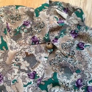  - Suupersnygg (!!!!) kort skjorta från Beyond Retro som tyvärr är för liten för mig. Den har knyt i midjan och är aldrig använd. Den har guld/brons-knappar och är i satinmaterial. 