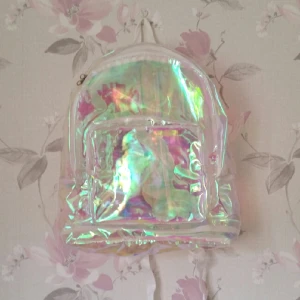  - Ryggsäck i 90 tals stil. Köpt i Japan Tokyo förra sommaren. Använd 2 ggr. Helt ny och grymt snygg. Skiftar i alla färger. Väskan är genomskinlig.