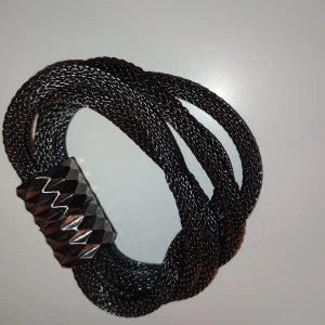 Supersnyggt armband - Stängs med magnet, treradigt i svart metall. Ena fotot med blixt och andra utan. 