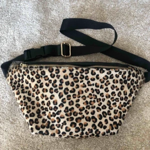  - Helt ny jättesnygg midjeväska i skinn med framsida i leopardmönster av kohår.  Mått ca 36x 20. Prislapp kvar. Säljes så jag har alldeles för många väskor.
