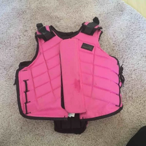  - Detta är en nästan ny, tuggummi råsa ridväst😃Den är från 7/8-11år😉Den har snören på sidorna och spännen längst upp. En dragkedja som man kan stänga västen med eller om man vill knäppa den