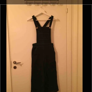  - Mörkblå jeanshängselbyxor med vida, lite kortare ben och kopparfärgade detaljer. Snygga året om, även till stövlar. Nyskick. Möts upp i Stockholm efter överenskommelse alternativt skickas mot fraktkostnad.