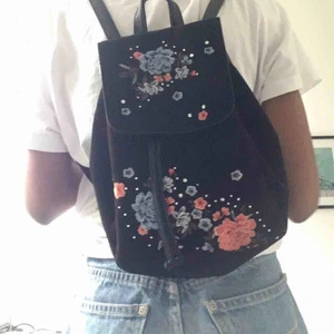 Ryggsäck med broderi - Söt ryggsäck i svart mockaimitation. Dekorerad med superfina broderade blommor och små kristallprickar. Justerbara band också. Använd några få gånger så den  är i bra skick. Pris kan diskuteras. Möts i Stockholm eller fraktar🎒🥰