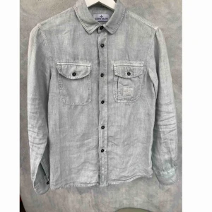  - Jag säljer en begagnad Stone Island skjorta, i bra skick. Storlek: 12 år / längd 152. Material: linne / bomull. Färg: ljusgrå. Nypris: ca. 1300 sek. 
