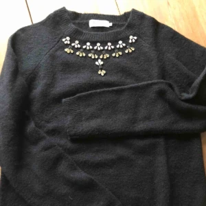  - Stickad tröja med pärlor på.