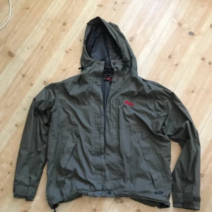  - Fjällräven skaljacka. Trevligt skick men Väl använd och det finns några mindre slitage men har många år kvar att ge. Litet hål (mindre än knappnål) på arm nära axel. Hängare lite lös, lätt fixat! Hämtas i Uppsala eller skickas spårbart för 58 sek