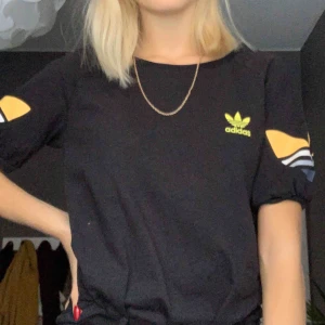  - Jätte snygg svart adidas t-shirt med gult tryck på ärmarna, ärmarna har även någon slags resår som gör de lite ”puffiga”. Det står på tröjan att det är stl 42 men den sitter bra på mig som är XS/S. Köpt på humana i Sthlm och är i mycket bra skick! 