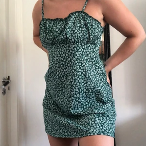 Grön blommig klänning - Grön klänning med vita blommor från H&M. Helt slutsåld! Storlek M men passar en S då jag sytt in den lite och det går att sy in mer! Kort i modellen. Tänk er ihop med en skinnjacka och boots!! 😍 150kr eller budgivning.