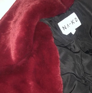 Kappa i fuskpäls - Vinröd i färgen och längre modell, jättemysig och varm kappa. Använd 3 gånger och inga skador så den är som ny. Köpt för 900kr, kan skickas. Köparen står för frakten.