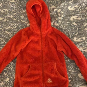 Kofta från Firefly - En röd tjock och fluffig kofta som passar super till vintern då barn oftast behöver en tjocktröja under exempelvis en regnhacka eller sådant!!