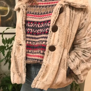 New York Yoki Pälsjacka - Hej! Jag säljer en fantastiskt varm och mysig jacka i beige fakepäls som passar perfekt till vintern och hösten🍁Den är i vintage-stil med stora bruna knappar. Den sitter inte tight och är lätt att röra sig i 👍👍 Skicket är bra med något slitna sömmar i fodret som inte stör! Om du vill ha fler bilder är det bara att lägga ett dm. Köparen står för frakt på 79kr!